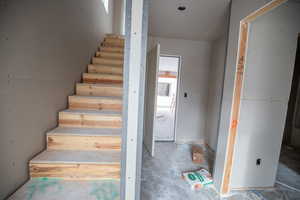 Staircase featuring unfinished concrete flooring