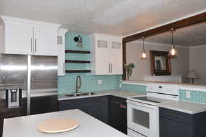 Kitchen with stainless steel fridge, white electric range, decorative backsplash, dishwasher, and a textured ceiling