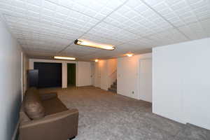 Unfurnished living room with stairs and carpet floors