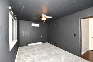 Empty room featuring carpet, ceiling fan, a baseboard radiator, and a wall mounted AC