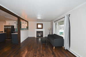 Living area with a fireplace with flush hearth, dark wood-style floors, a textured ceiling, and baseboard heating