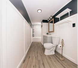 Bathroom with vanity, bathing tub / shower combination, and light wood-style flooring