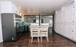 Kitchen featuring appliances with stainless steel finishes, white cabinets, a kitchen breakfast bar, light countertops, and a textured ceiling
