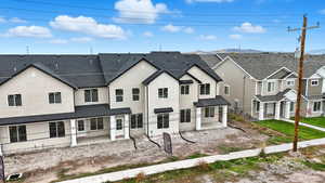 Back of house featuring a patio area, stucco siding, a shingled roof, and a residential view