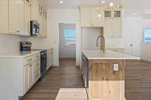 Kitchen featuring glass insert cabinets, range with electric cooktop, a center island with sink, decorative light fixtures, and light wood finished floors