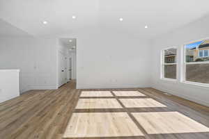Unfurnished room featuring light wood finished floors, lofted ceiling, and recessed lighting