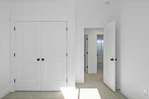 Unfurnished bedroom with light colored carpet and a closet