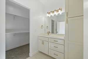 Bathroom with a walk in closet, vanity, and light carpet