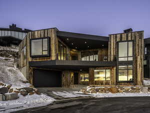 Modern home with a balcony, an attached garage, and driveway