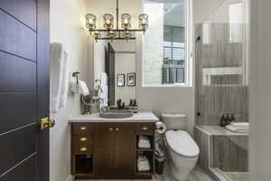 Bathroom featuring vanity, a stall shower, and a chandelier