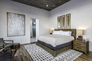 Bedroom with wooden ceiling, connected bathroom, dark wood-type flooring, and recessed lighting