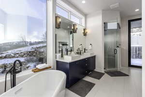 Bathroom featuring a stall shower, a soaking tub, double vanity, recessed lighting, and light tile patterned flooring