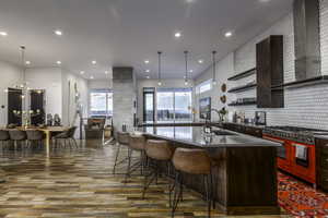 Kitchen with wall chimney range hood, open shelves, a large island, double oven range, and a breakfast bar