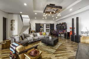 Living room with a tray ceiling, recessed lighting, light wood-type flooring, and stairway