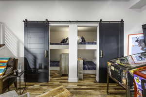 Bedroom with a barn door, wood finished floors, and a walk in closet