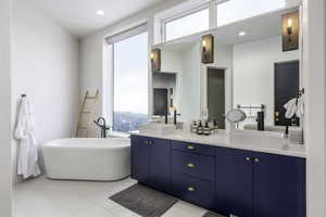 Bathroom with double vanity, a soaking tub, recessed lighting, and light tile patterned flooring