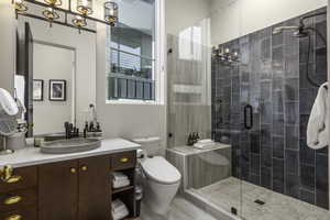 Bathroom featuring vanity, a stall shower, and a chandelier