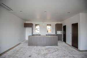 Kitchen featuring a kitchen island, dark brown cabinetry, a textured ceiling, and modern cabinets