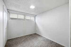 Unfurnished bedroom with a textured ceiling, a closet, and carpet