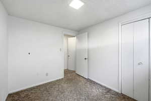 Unfurnished bedroom with a textured ceiling, carpet floors, and a closet
