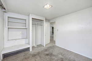 Unfurnished bedroom featuring a textured ceiling, carpet floors, and a closet