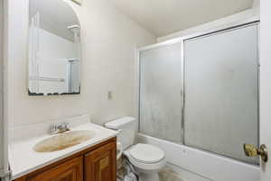 Bathroom with vanity and bath / shower combo with glass door