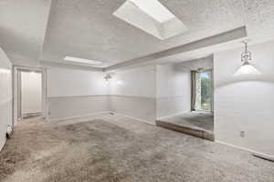 Carpeted empty room featuring a textured ceiling and baseboards
