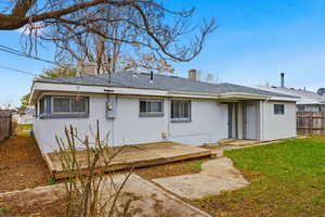Rear view of property featuring a chimney, a deck, brick siding, and roof with shingles