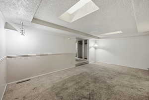 Finished basement featuring carpet flooring, a textured ceiling, and concrete block wall