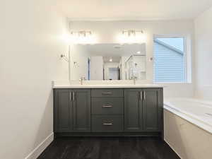 Full bathroom with double vanity, a bath, a shower stall, and dark wood-type flooring