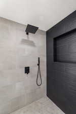 Bathroom with a textured ceiling and tiled shower