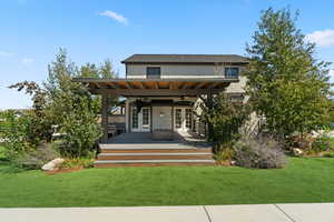Back of house with french doors, a ceiling fan, stucco siding, and a yard
