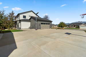 View of side of home featuring concrete driveway, an attached garage, board and batten siding, and a mountain view