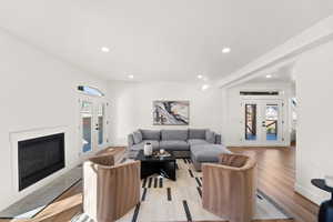 Living room featuring french doors, recessed lighting, light wood-style floors, and a glass covered fireplace