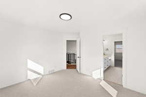 Unfurnished bedroom with light carpet and ensuite bath
