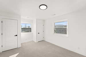 Unfurnished bedroom featuring light carpet and baseboards