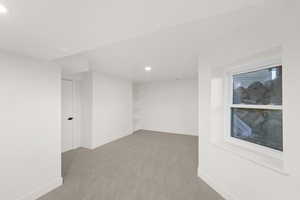 Below grade area with light colored carpet, recessed lighting, and built in features