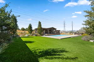 View of grassy yard with a patio area and an outdoor structure