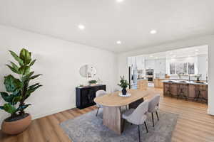 Dining area with light wood finished floors and recessed lighting