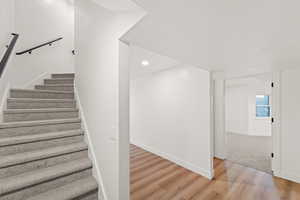 Staircase featuring wood finished floors and recessed lighting
