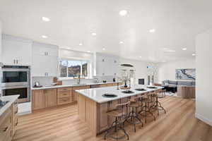 Kitchen with appliances with stainless steel finishes, a kitchen bar, light wood-type flooring, light brown cabinets, and open floor plan