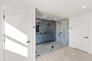 Bathroom featuring double vanity, a shower stall, recessed lighting, and tile patterned floors