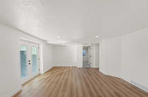 Empty room featuring french doors, light wood-style flooring, and recessed lighting