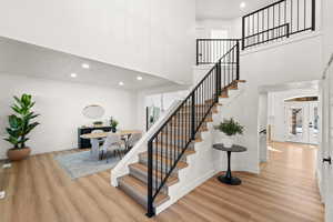 Stairs featuring recessed lighting, a high ceiling, french doors, and wood finished floors