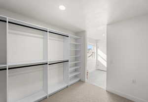 Walk in closet featuring light colored carpet