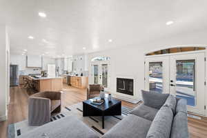 Living area featuring french doors, light wood-type flooring, recessed lighting, and a glass covered fireplace