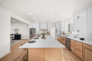 Kitchen featuring a breakfast bar, light stone counters, light wood-style floors, stainless steel appliances, and a center island
