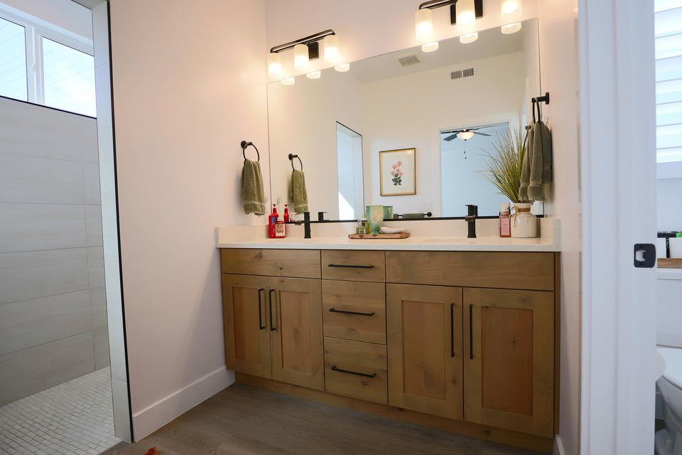 Full bath featuring double vanity and dark wood-type flooring