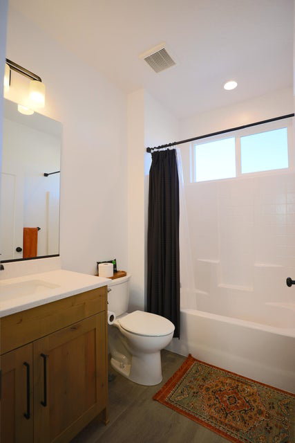 Full bath with dark wood-style flooring, shower / bath combination with curtain, vanity, and recessed lighting