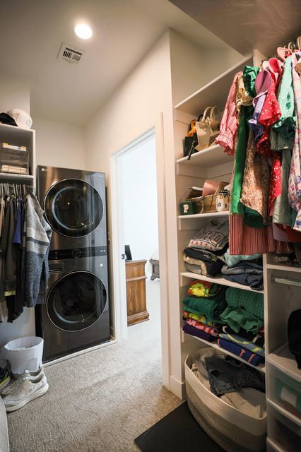 Washroom featuring stacked washer and clothes dryer, light colored carpet, and recessed lighting